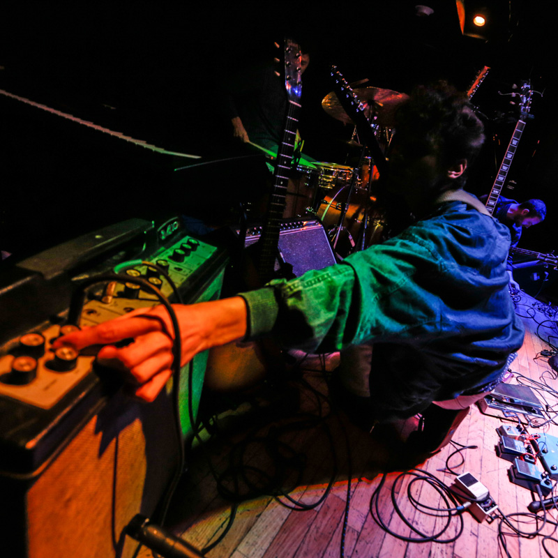 Guitarist on stage adjusting amp